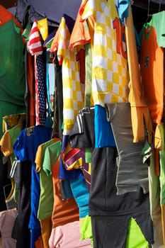 A selection of colorful t-shirts hanging on a rack in the market of Mopti in Mali