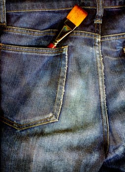 Art brush in a back pocket of a pair of blue jeans in rough grunge.