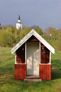 Small red playhouse with a church in the background