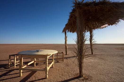 Chairs and a table on cracked dry mud in Morocco