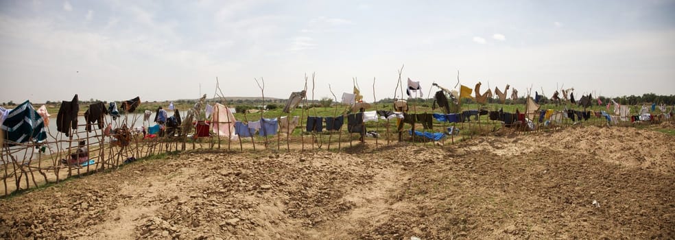 Panoramic view of clothes hanging and drying on pieces of wood in Senegal