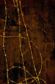 Barbed wire against a grungy old wall in dark brown.