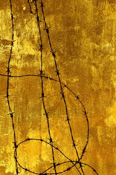 Barbed wire against a grungy old wall in sepia.