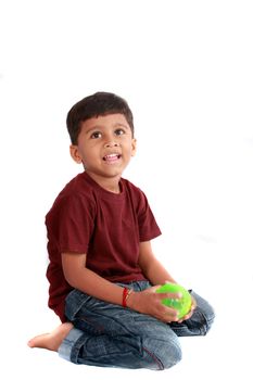 An Indian boy sitting with a ball, on white studio background.