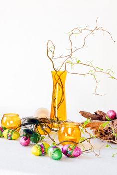 Easter decoration with yellow glass-ware and chocolate eggs - vertical