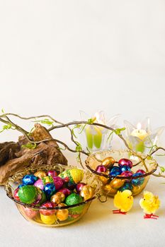 Easter decoration with chocolate eggs in yellow glass bowls - vertical