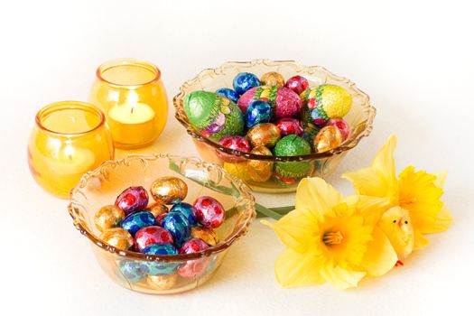 Easter decoration - yellow glass bowls with chocolate eggs, candles and daffodils