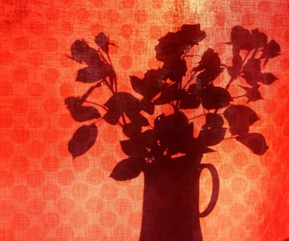 Silhoutte of roses in tall vase behind red curtain