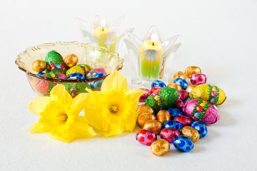 Easter decoration with chocolate eggs, daffodils and candles