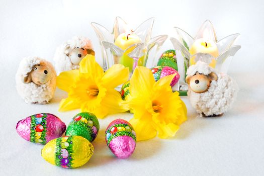 Easter decoration with sheep, chocolate eggs, daffodils and candles