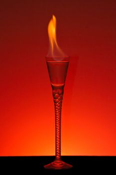 Alcohol burning in beautiful handmade glass with burning red background