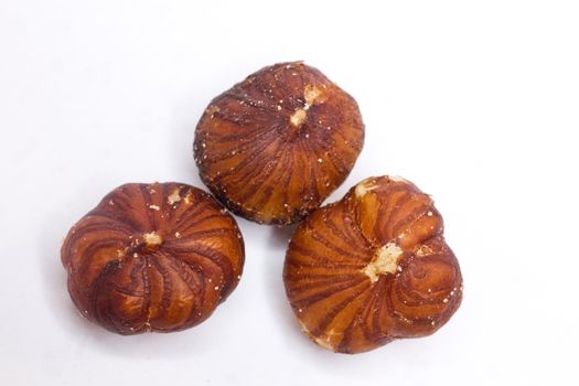 Close-up of three unshelled roasted and salted macadamia