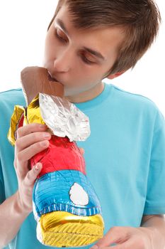 A child bites the ear of a milk chocolate bunny.  White background.