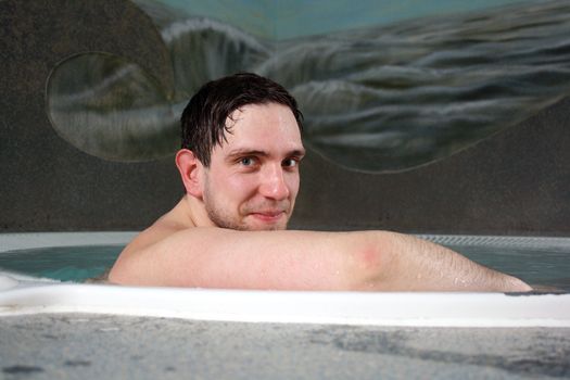 A pretty boy is lying relaxed in the pool 