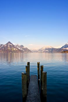 Empty dock in calm lake with mountains in the horizon. Buochs, Switzerland.