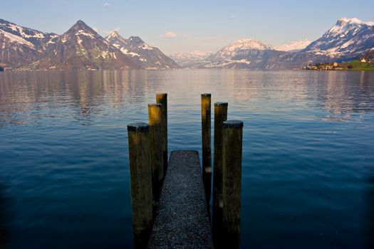 Empty dock in calm lake with mountains in the horizon. Buochs, Switzerland.