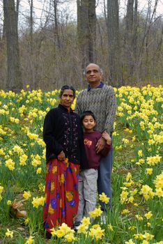 An Indian Kid with grandparents in a field of daffoldils