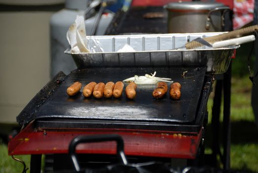 Hots dogs and onions on an outdoor grille