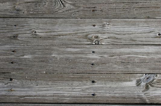 Close up of sandy, weathered planks on beach walkway