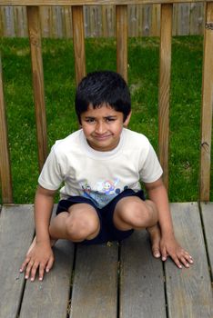 an unhappy indian kid sitting on a deck