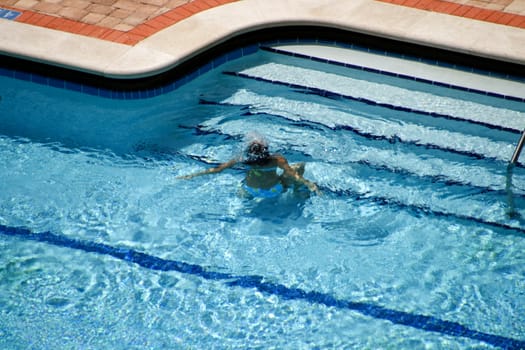 Woman in Pool Underwater was captured as she submerged herself to wet her hair prior to exiting via the nearby steps.
