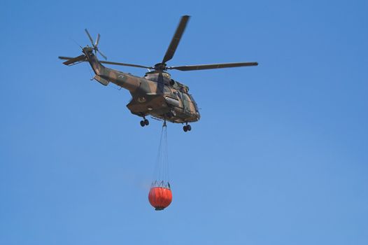 Air-Force Helicopter with a Bambi Bucket filled to fight a forest fire