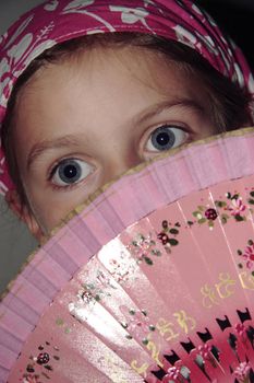 a girls face hidden behind a fan