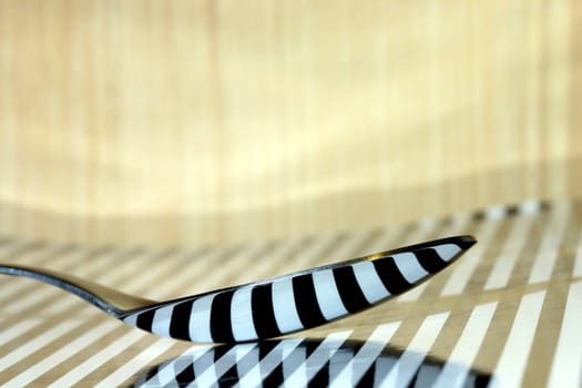 Spoon on stripped surface with reflection