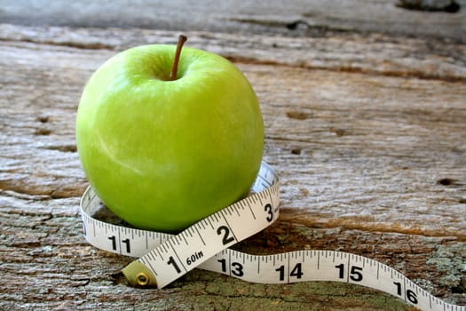 measuring tape wraped around a fresh green apple.
