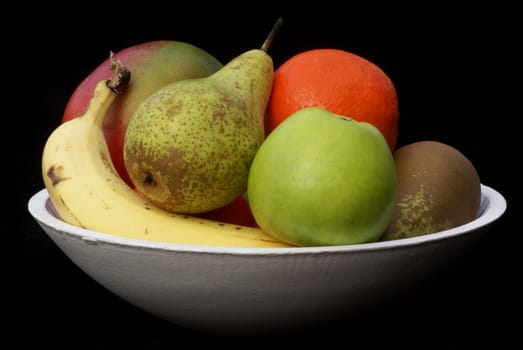 Bowl with fruit isolated on a black background.
