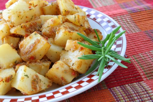 A side dish of potatoes and seasoning with a twig of fresh Rosemary.