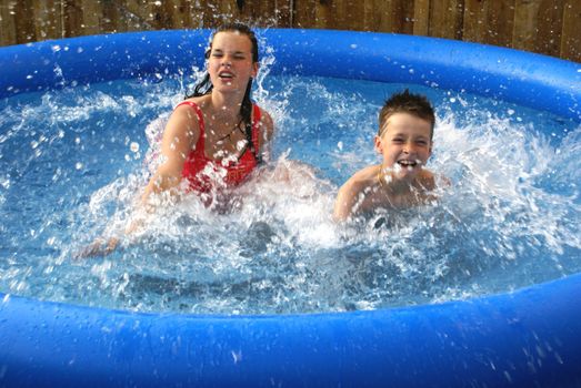 Two kids splashing in pool.                