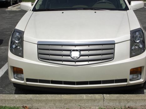 A car with vertical headlights, a thick bumper and a grill, is in a parking lot.