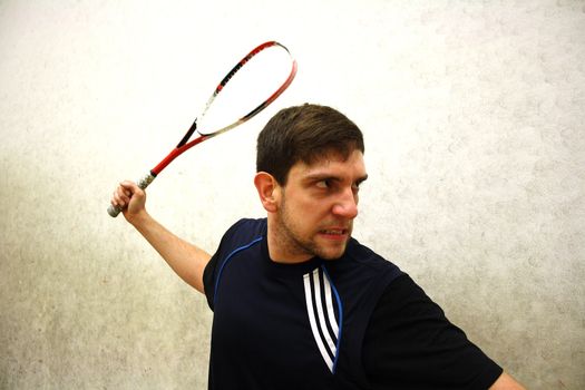 A handsome man playing squash in the hall 