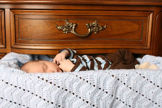 One month old baby boy sleeping in a drawer