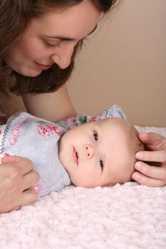 Beautiful brunette mother looking at her two month old baby girl 