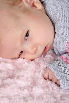 Beautiful baby girl on a pink blanket 