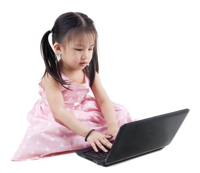 Beautiful little girl sitting on floor using a laptop, white background