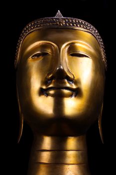 A metallic idol of a Buddha idol, on black studio background.