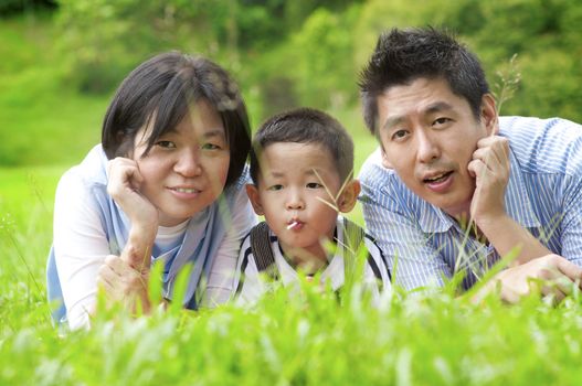 Asian outdoor family lying on green field