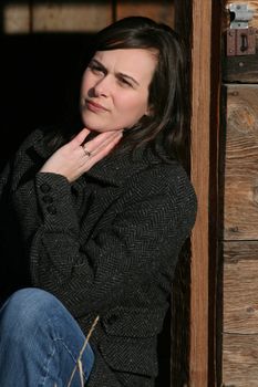 Beautiful brunette female leaning against wooden barn