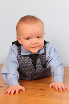 Cute baby boy crawling on a wooden floor
