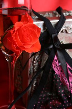 Glass of champagne with rose, underwear in the background