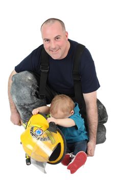 Fireman father and his toddler son looking into his hat