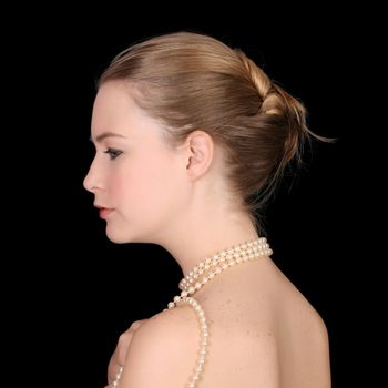 Beautiful blond female wearing pearls against a black background