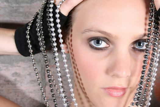 Beautiful model with blue eyes holding strings of beads 
