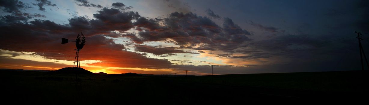 Old Farm Windmill for Pumping Water with Spinning Blades at Sunset in South Africa