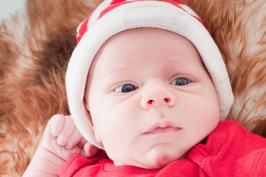 Newborn baby in chritstmas hat lies on fur