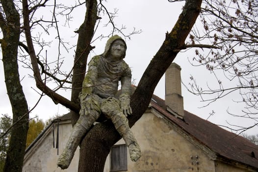 Terrible the sculpture of the person sits on a tree