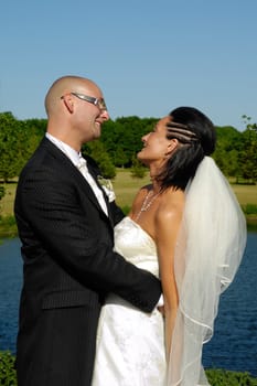 Bride and groom are standing close together looking at each other.